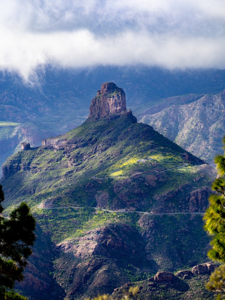 Patches of light hit Roque Bentayga while thick clouds roll above it