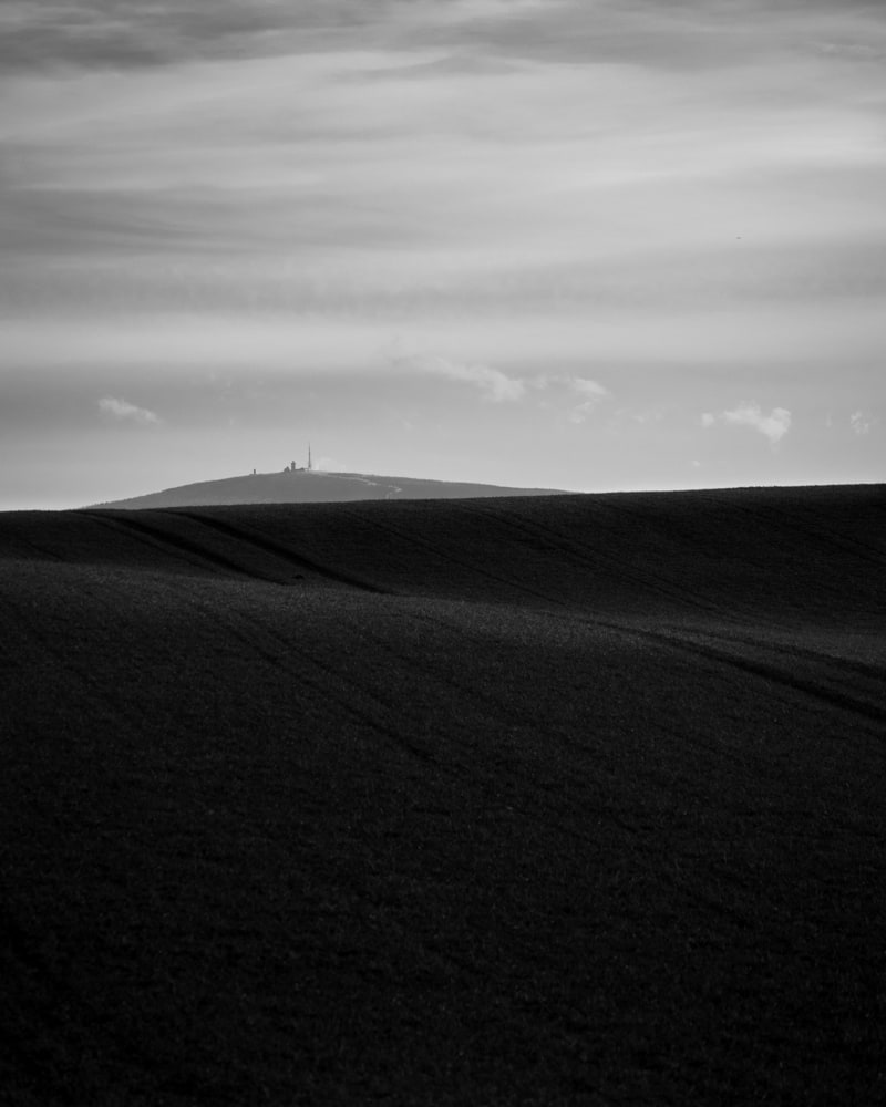 The top of the Broken mountain is seen behind a smooth hill in black and white