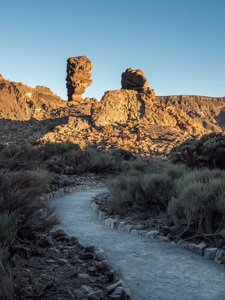 A foot path leads to the Roque Cinchado illuminated by the setting sun.