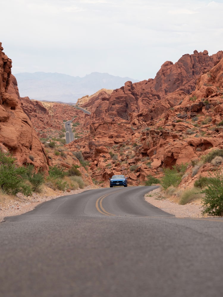 A blue Ford Mustang driving towards the camera in Valley of Fire State Park in Nevada