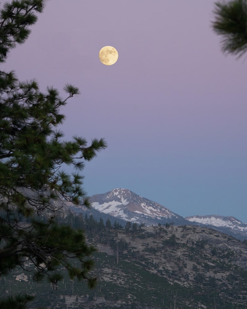 The moon rises just after sunset to the south of Half Dome